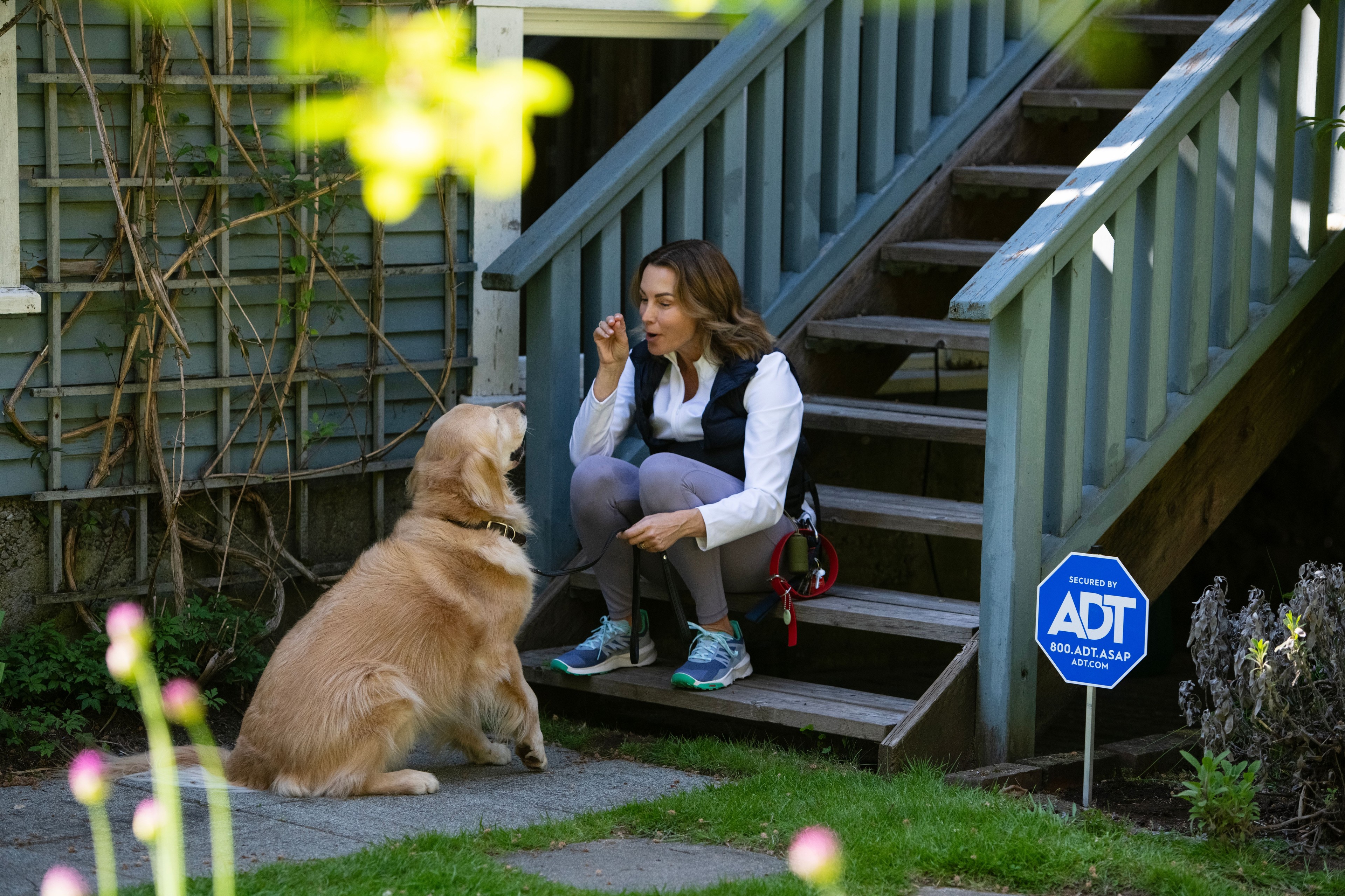 Woman on porch with dog and ADT sign