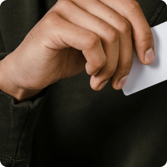 Hand in dark green sleeve holding a white card.