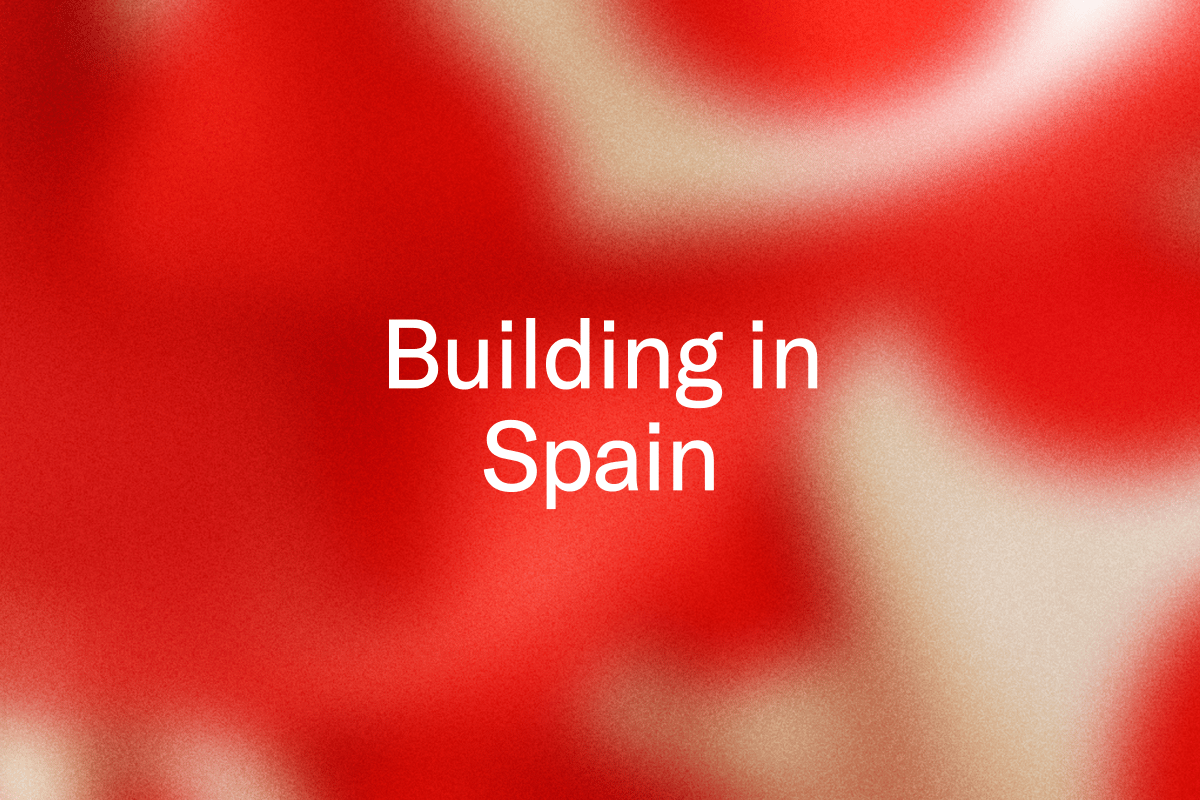White text "Building in Spain" on a blurred, grainy red and cream background