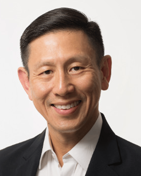 Smiling East Asian man in a black suit.