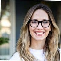 Smiling woman with long blonde hair and black glasses.