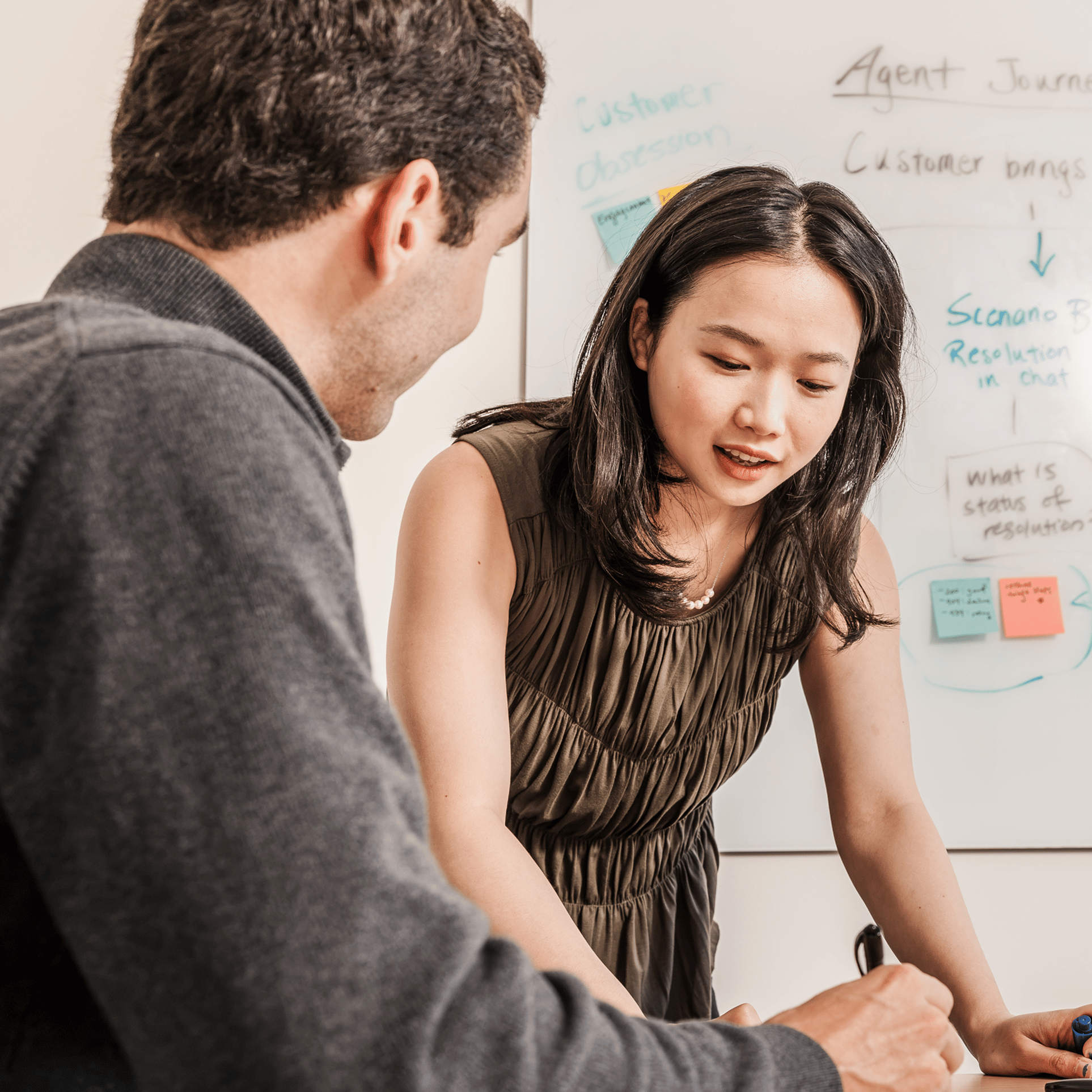 white board in the background with woman explaining concept to man