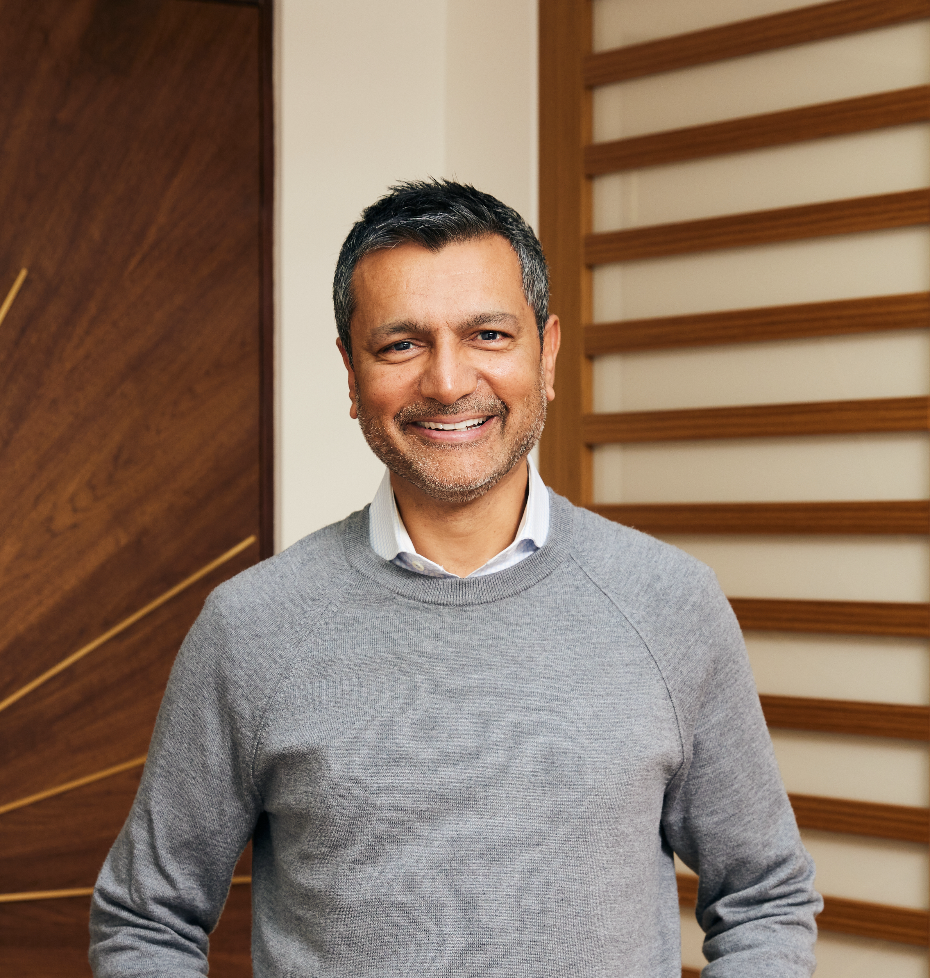 Dharam Rai, SVP of Customer Success at Sonos, sitting on a couch smiling