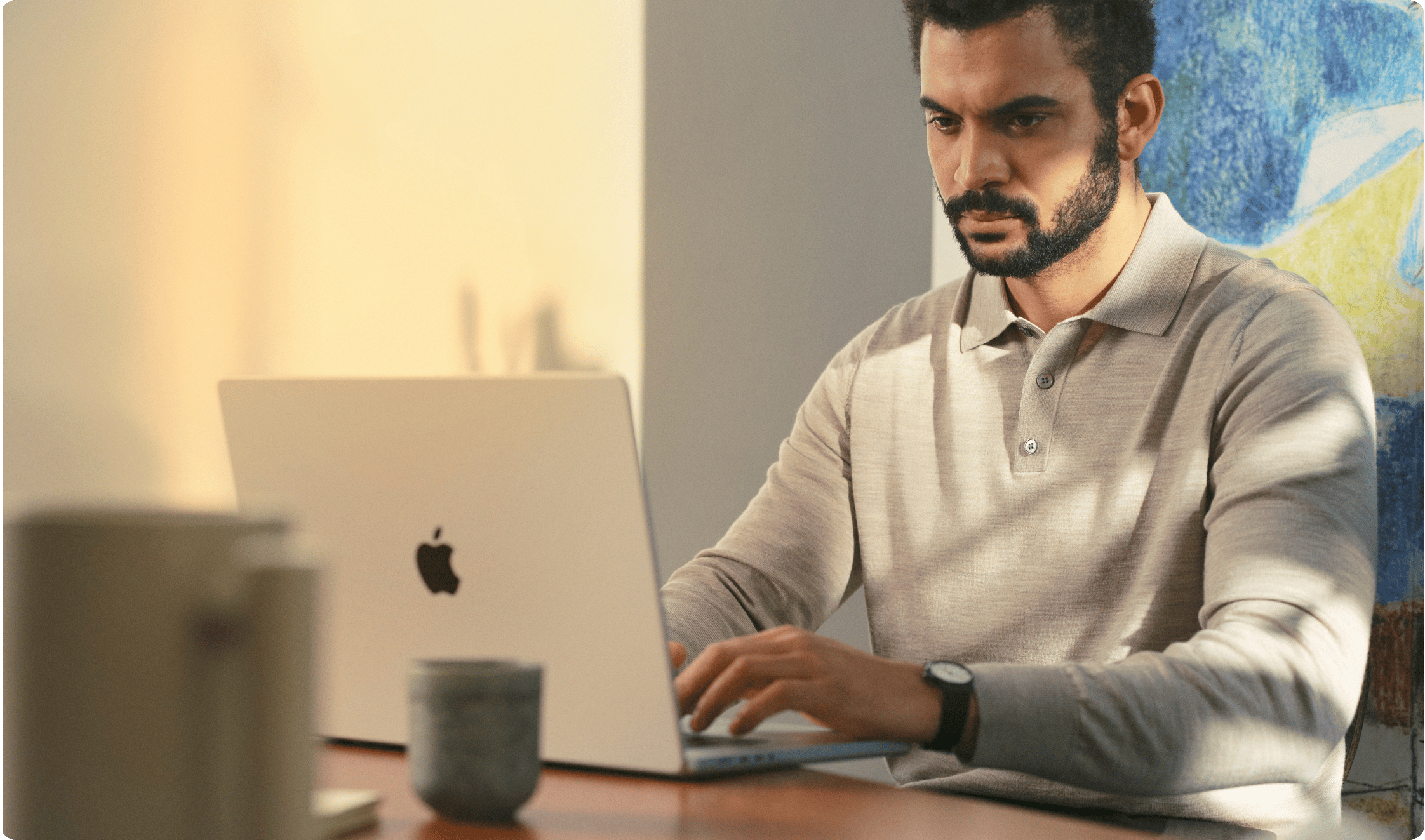 A man sits at a table and types on his computer.