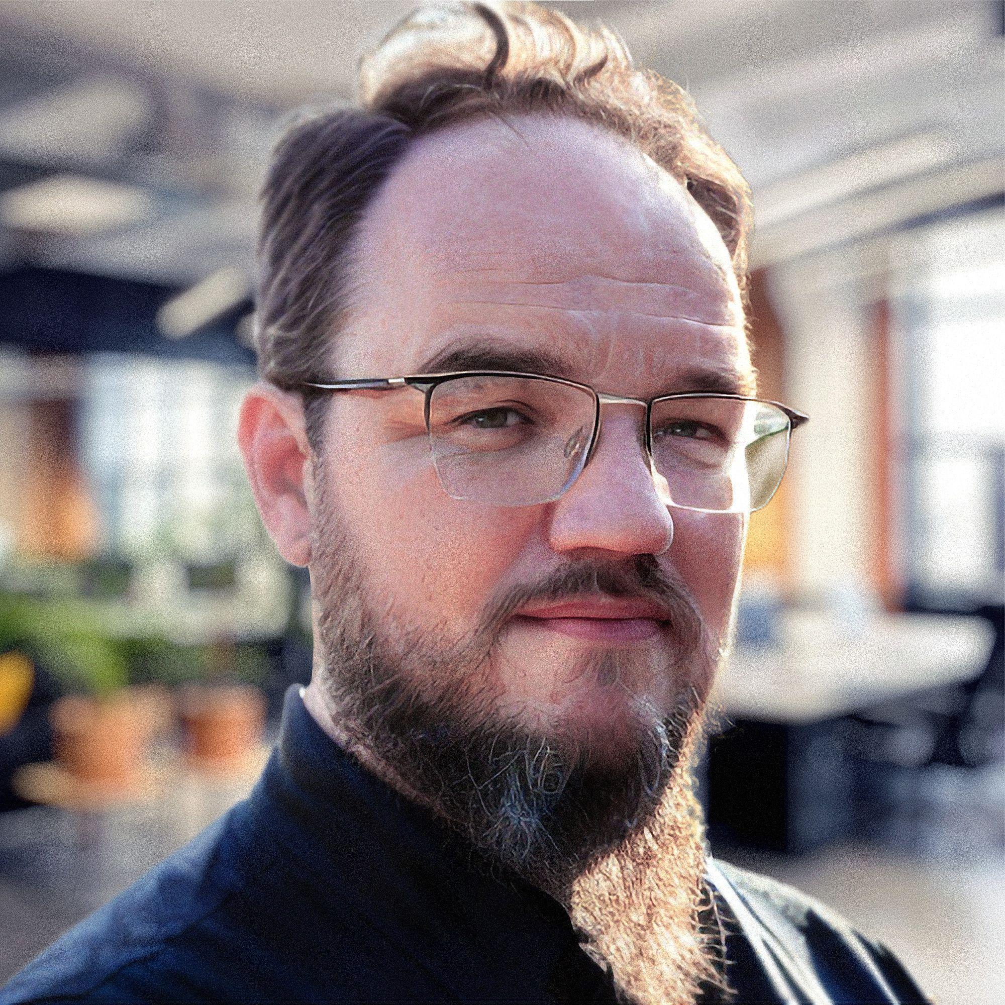 Headshot of a man with glasses and a beard.