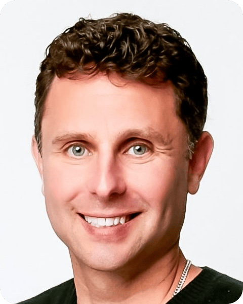 Headshot of a smiling man with curly brown hair and light eyes.