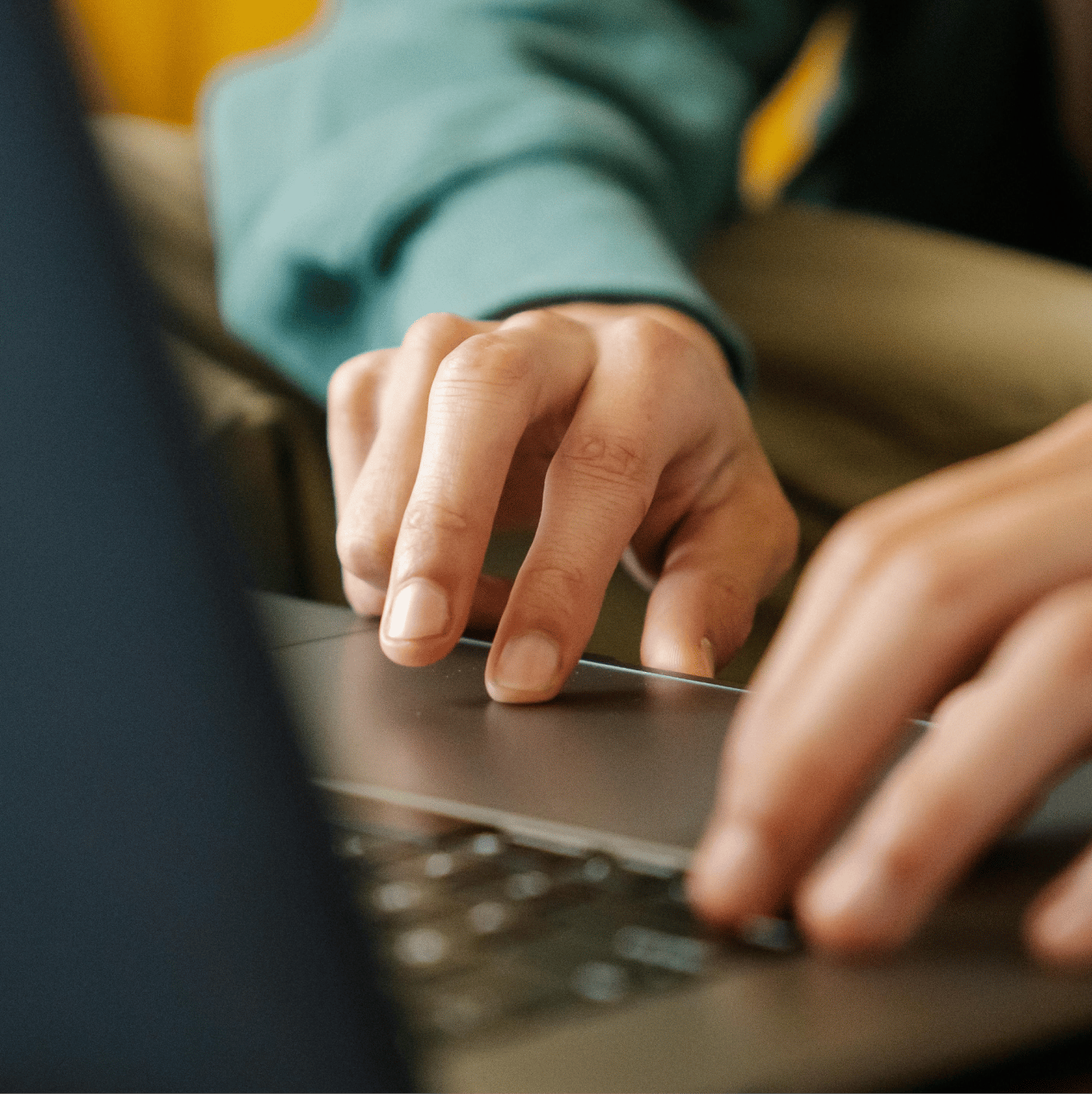 Hands using a laptop keyboard and trackpad.