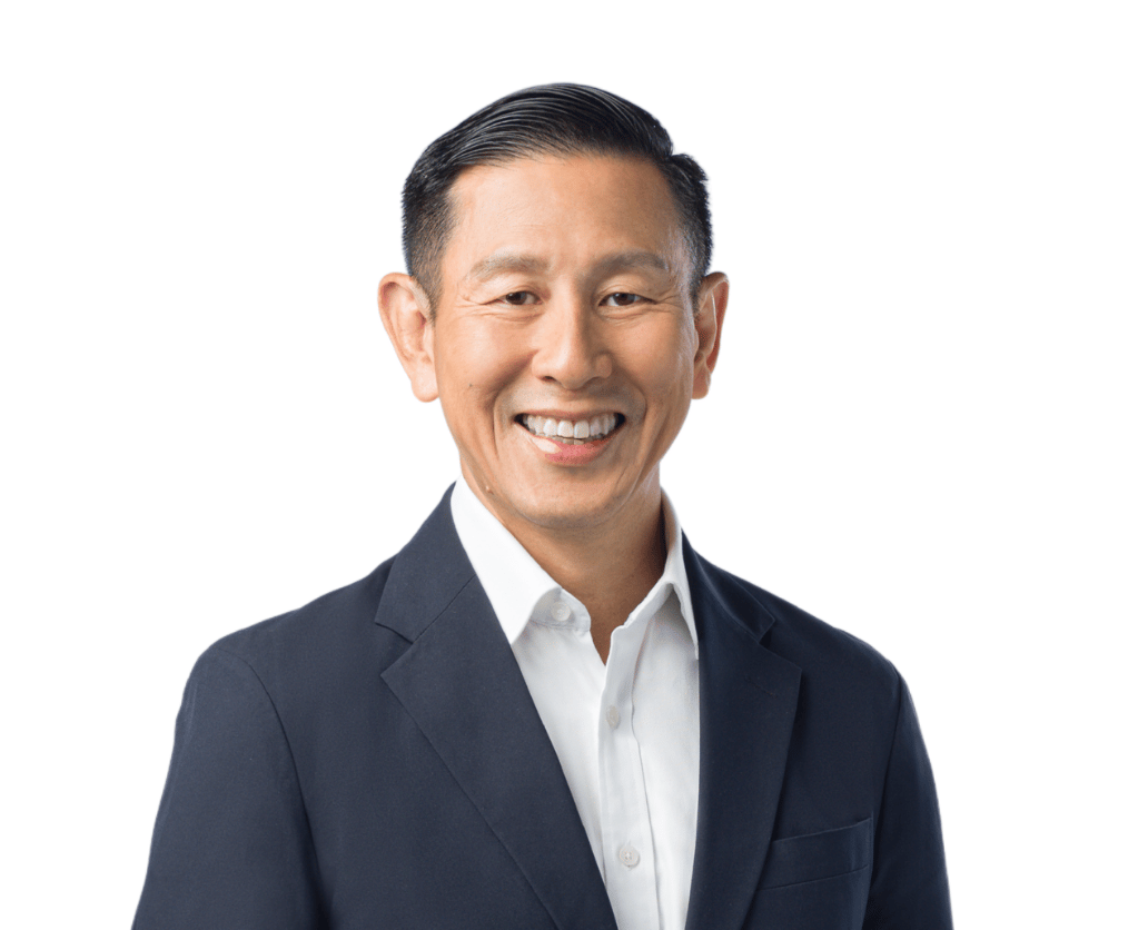 Smiling East Asian man in a dark suit jacket and white shirt against a white background.
