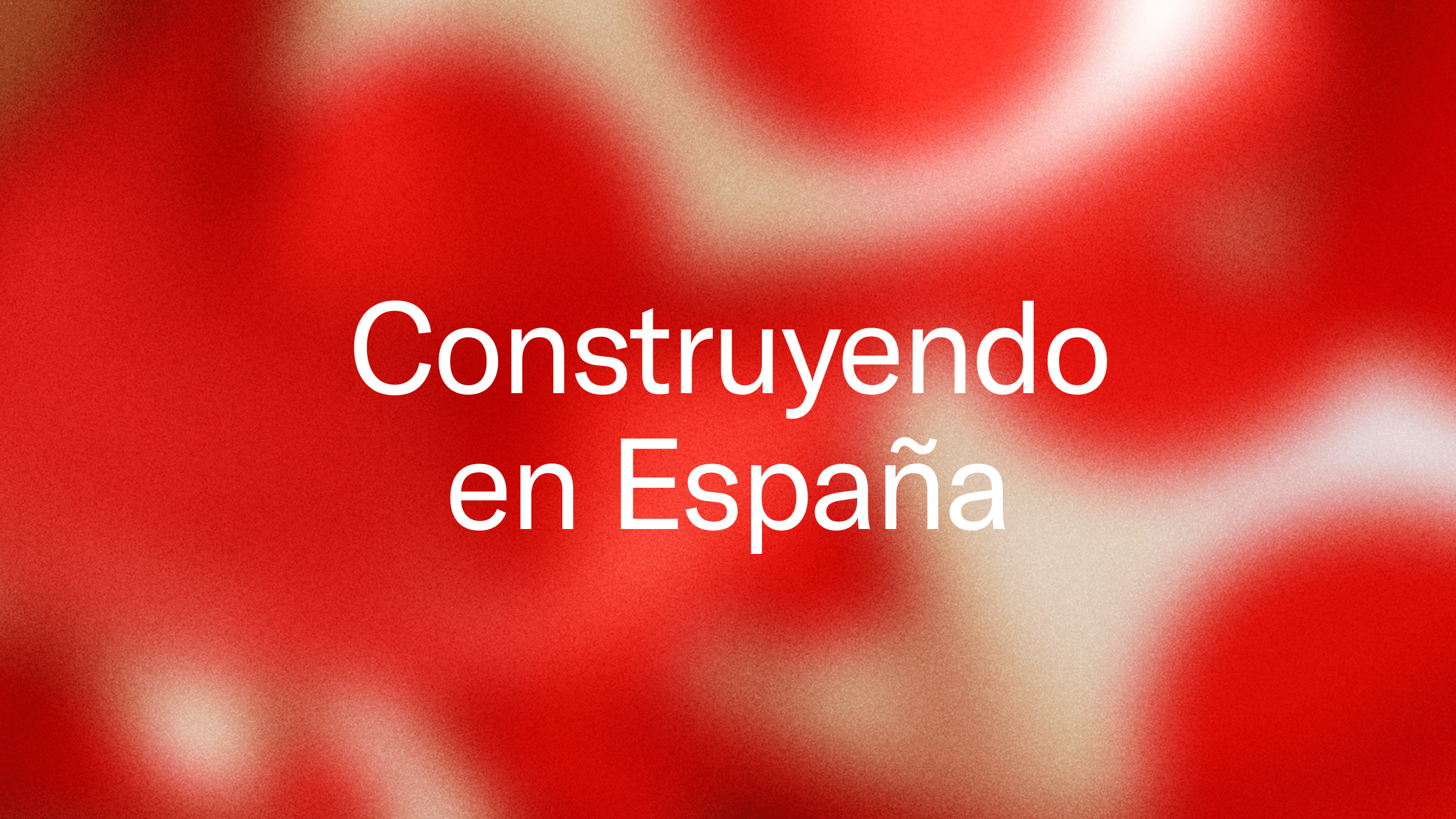 White text "Construyendo en España" (Building in Spain) on a blurred red and white background.